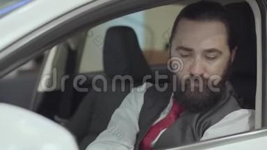 这幅画中有着迷人的、自信的留着胡须的人坐在车里，检查从车里买的新车